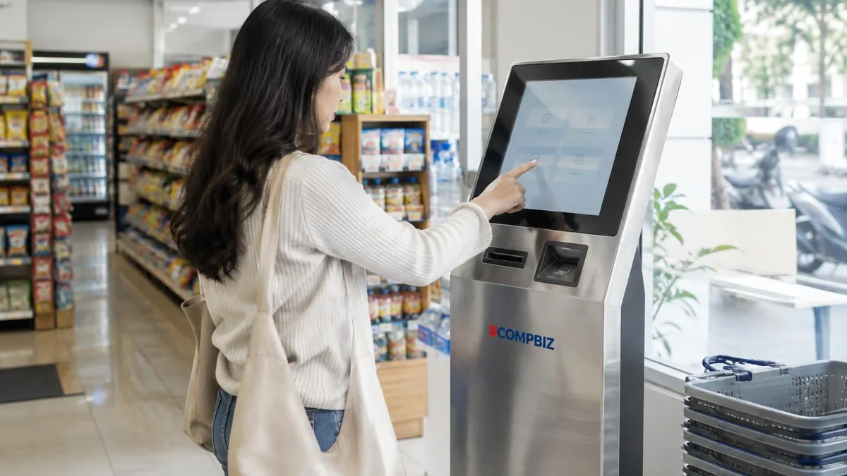 Pelanggan menggunakan kiosk self-service di dalam minimarket